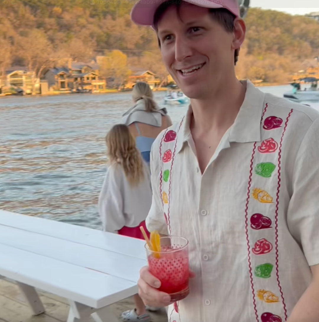Man holding a drink by a lake with people in the background